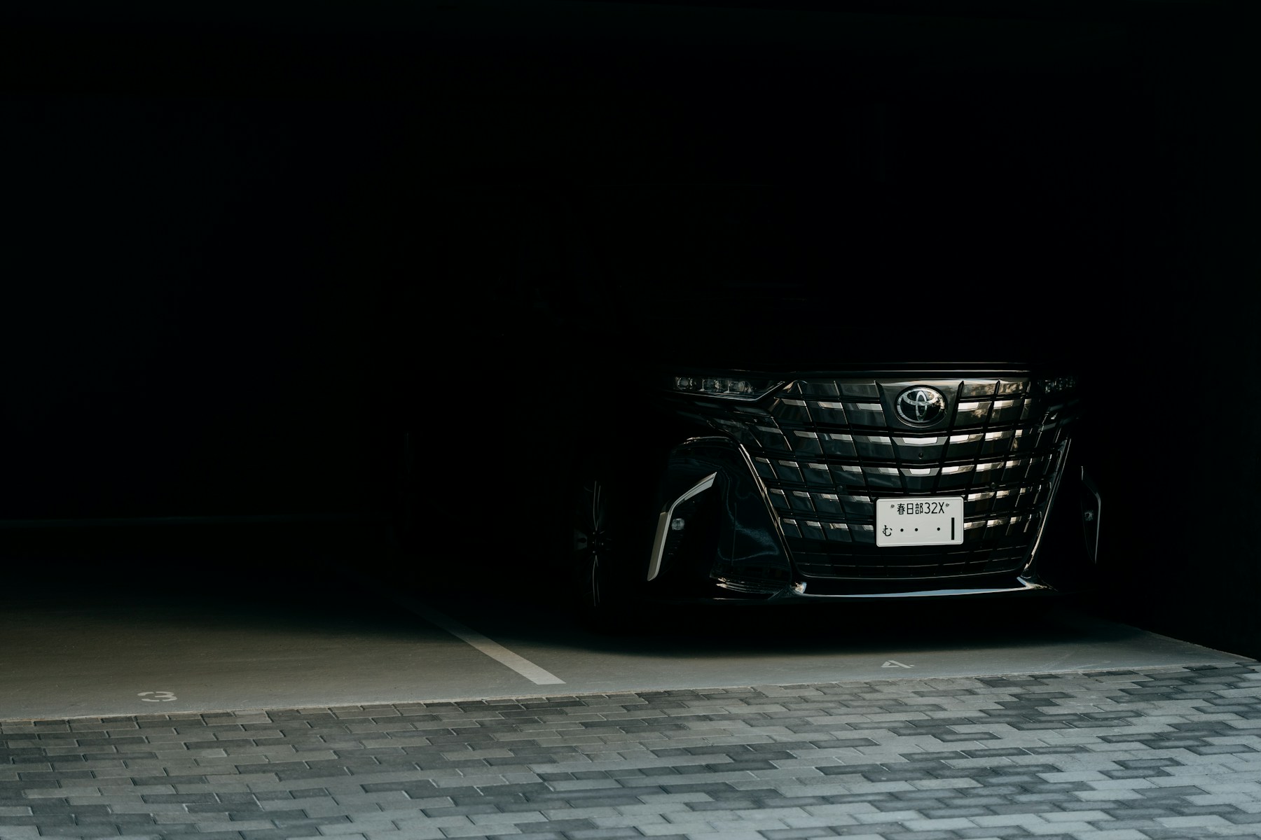 Dark vehicle front end in a shadowed garage